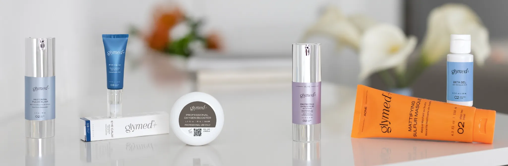 Assorted skincare bottles, tubes, and a small device displayed on a clean white surface.