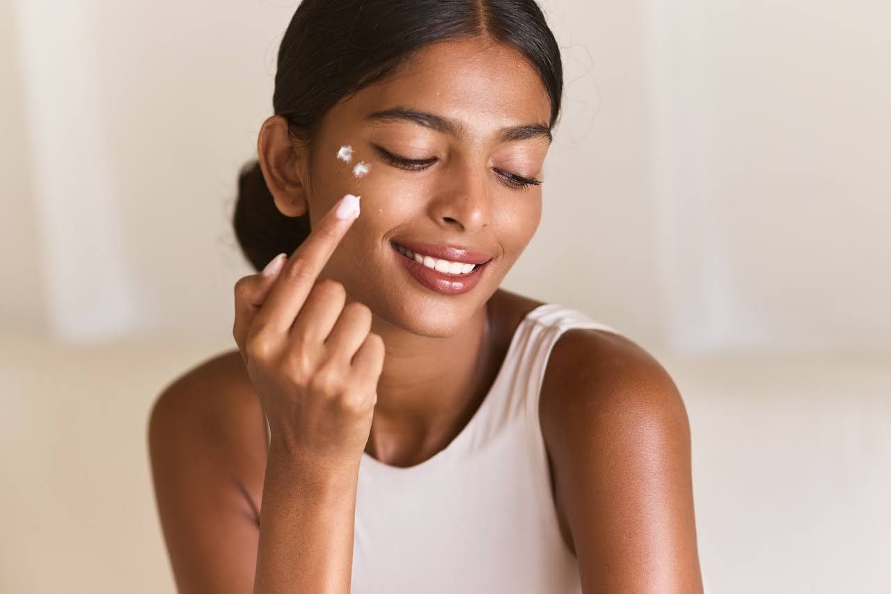 Woman applying face cream with fitzpatrick skin type V