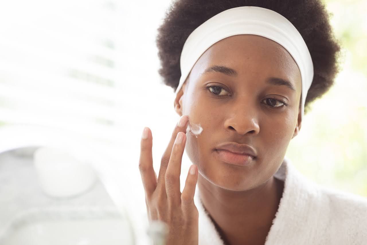 Woman applying hydrating moisturizer to balance skin pH levels