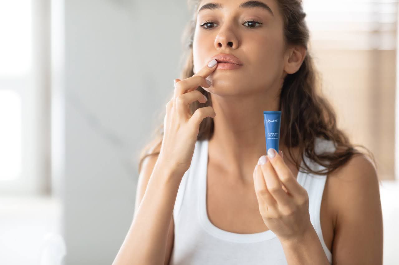 Woman applying lip balm as part of winter skincare routine