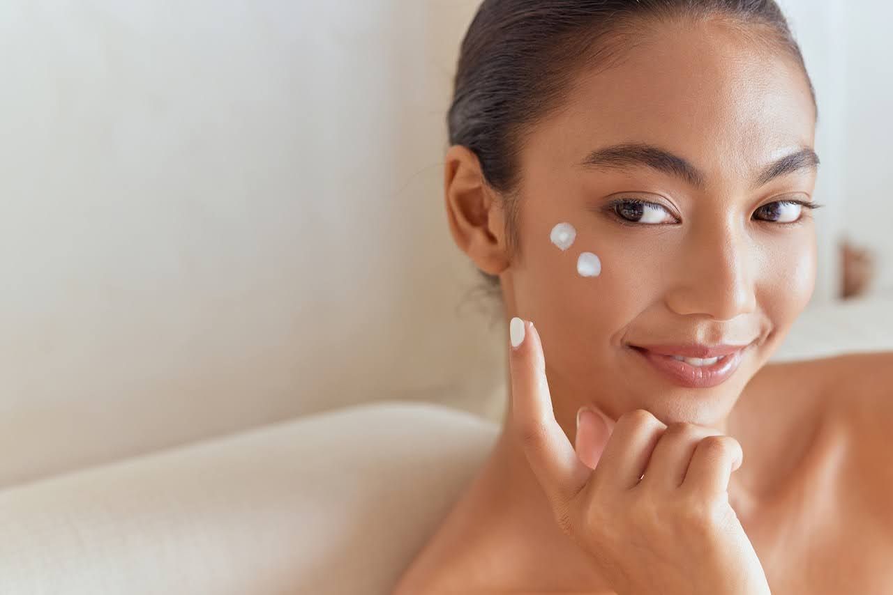 Woman applying moisturizer to dry skin