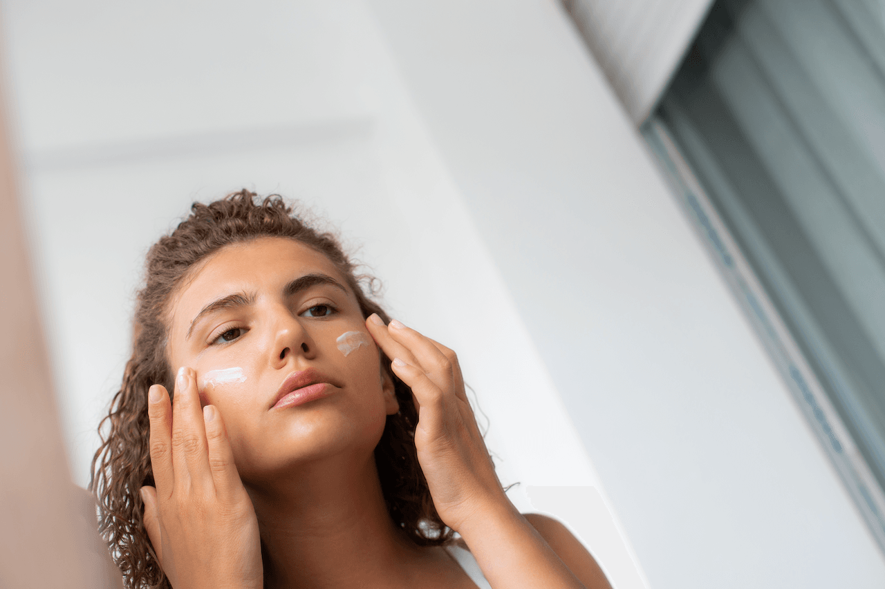 Woman applying sunscreen after microneedling