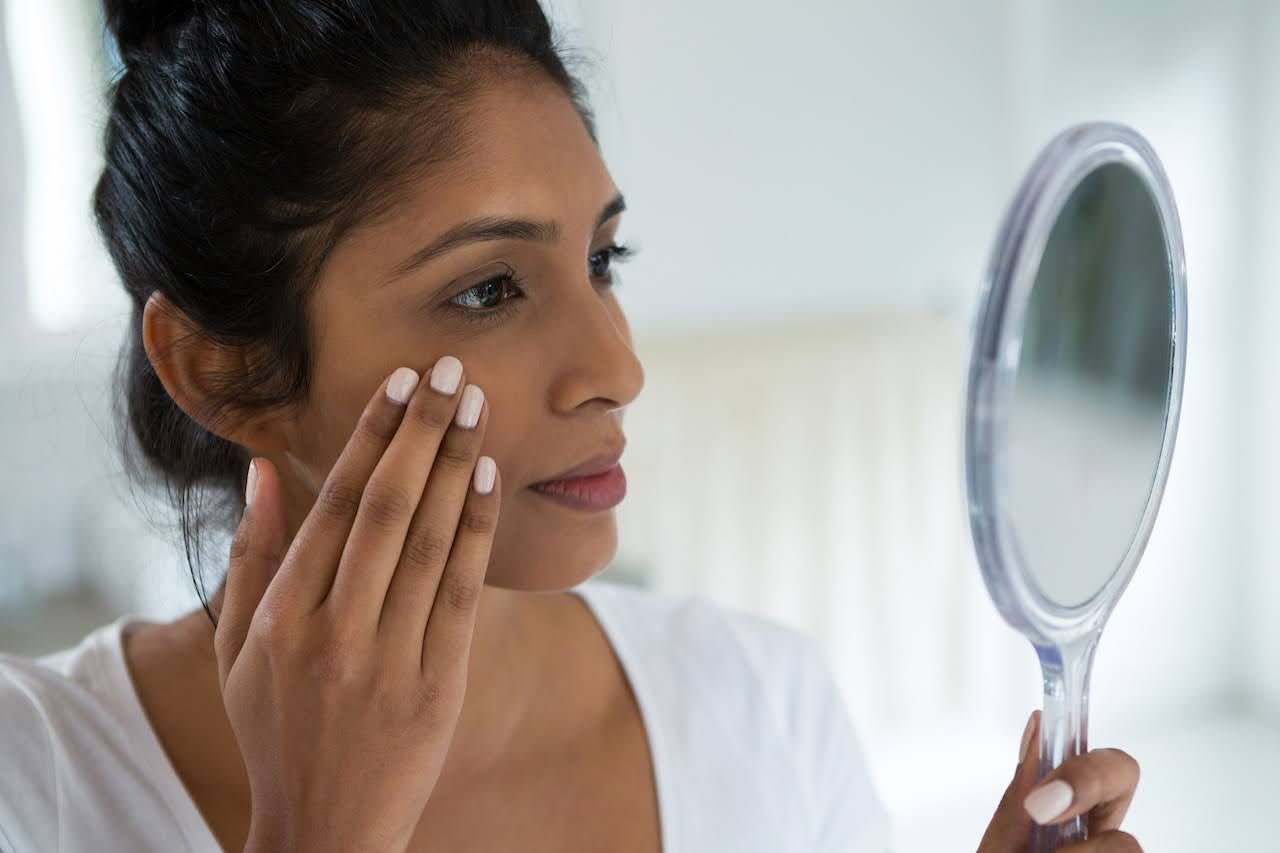 Woman checking skin after using skin brightening products