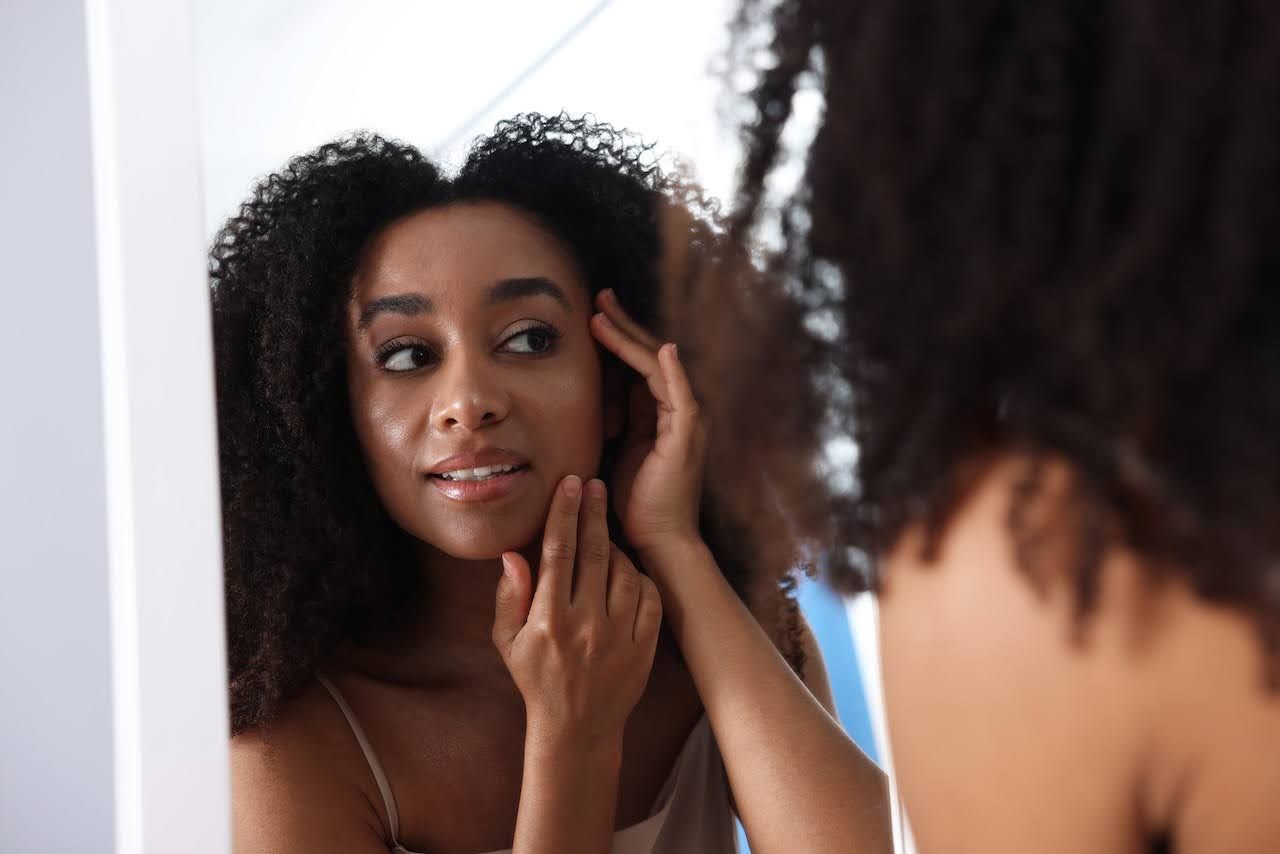 Woman looking at skin in the mirror after receiving treatment
