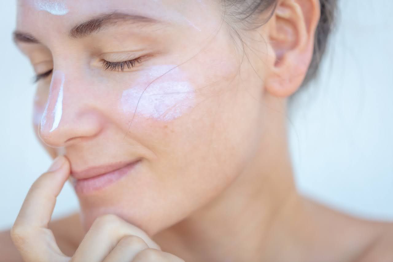 Woman putting sunscreen on to help skin post procedure