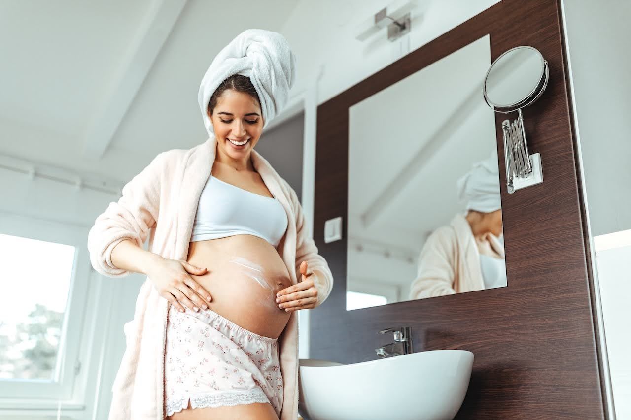 Woman using pregnancy safe skincare to prevent stretch marks