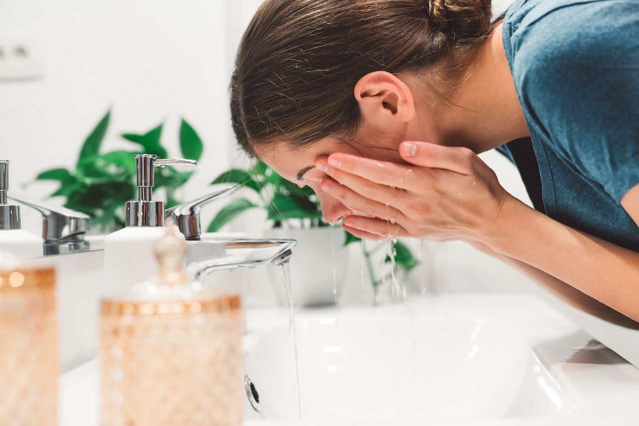 Woman washing face to help manage acne