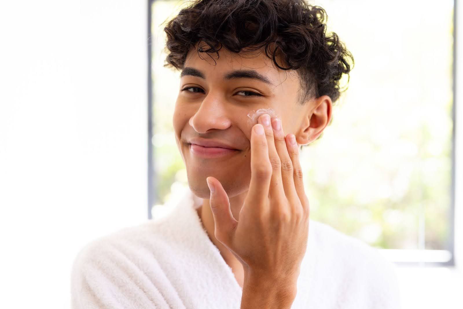 Young man applying moisturizer during skincare routine