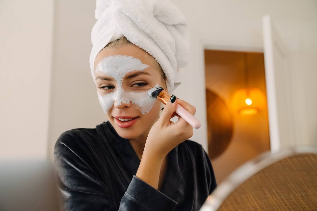 Young woman applying face masque to help improve skin