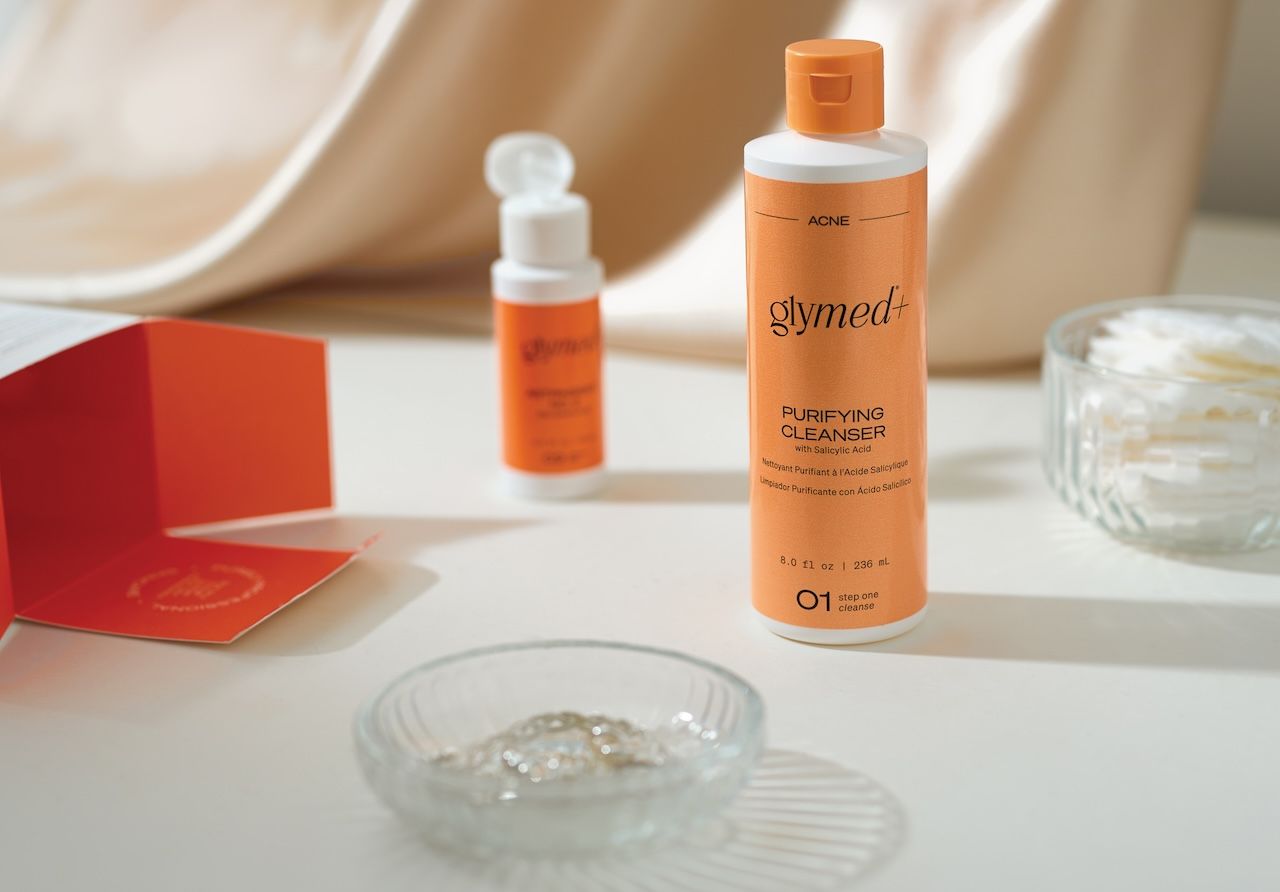 Bottle of GlyMed+ purifying cleanser and other skincare products designed for different types of acne