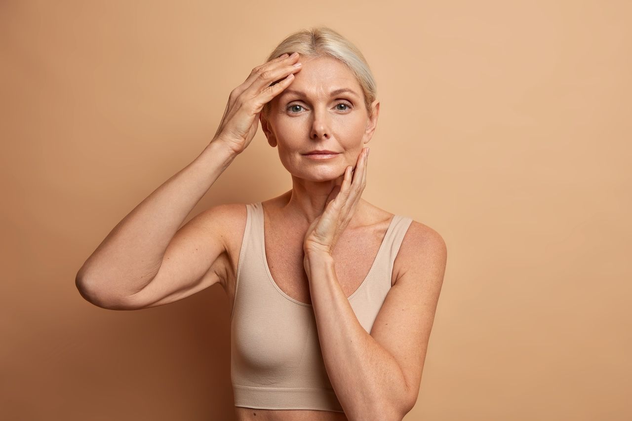 mature woman touching her skin and stressed about persistent skin concerns