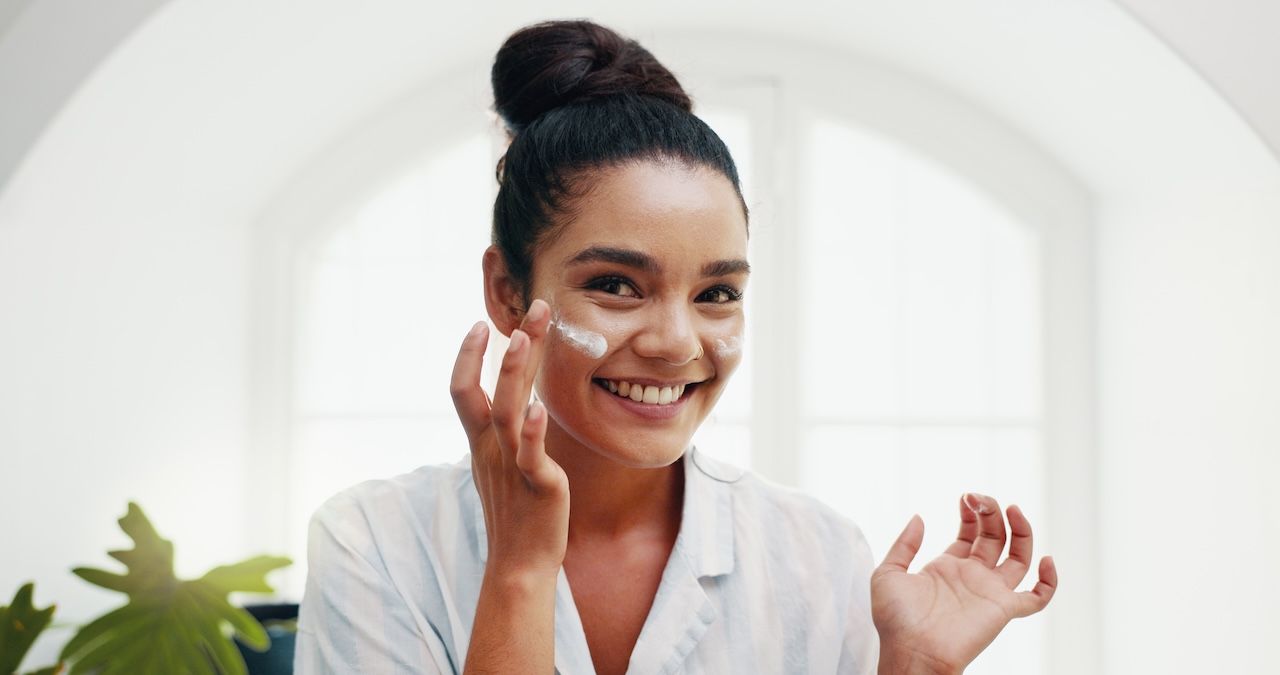 woman applying facial moisturizer to cheeks during skincare routine