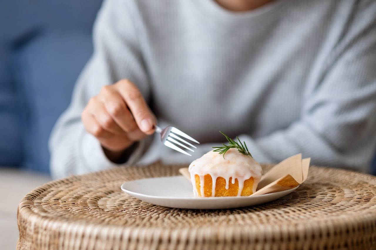 person eating a sweet muffin representing dietary sugar as a factor in skin glycation