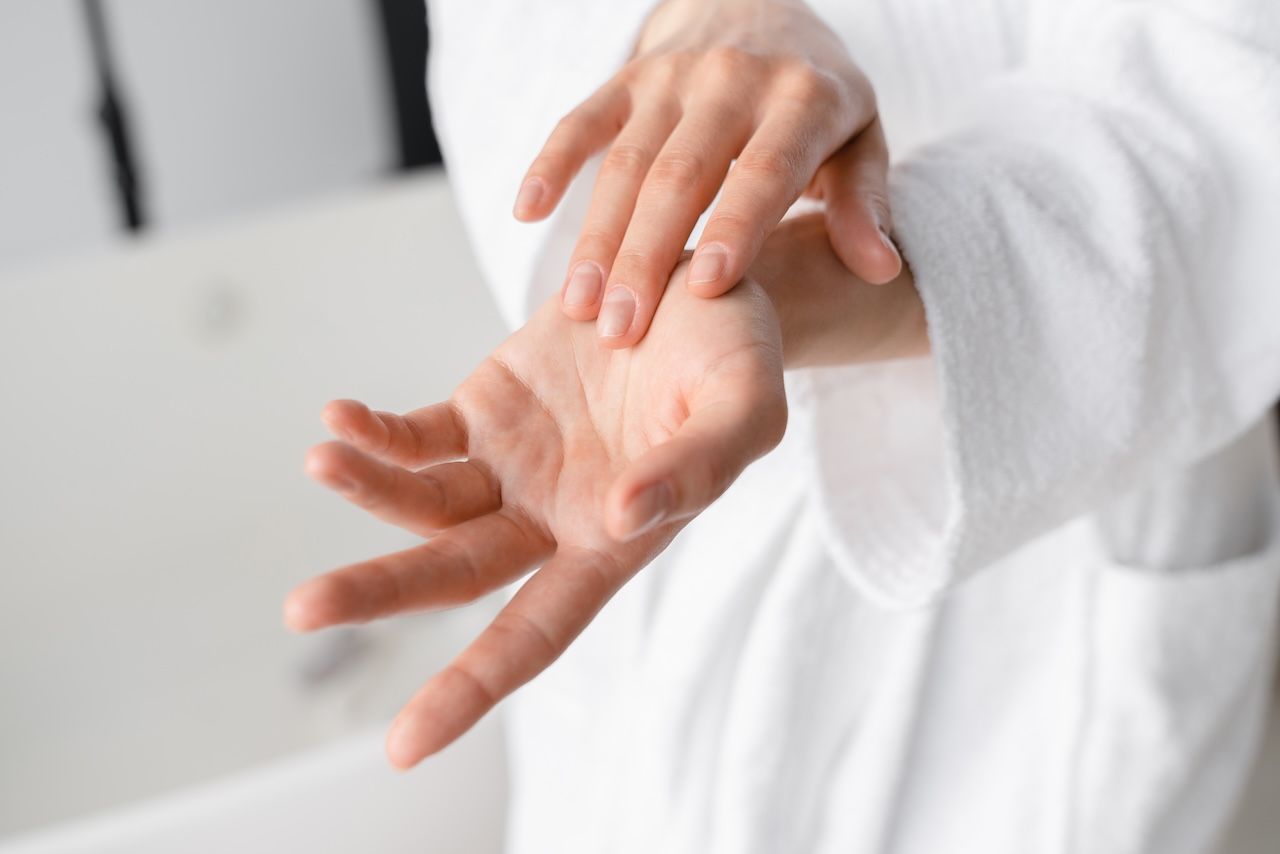 close-up of hands applying moisturizer to skin to improve hydration and relieve dryness