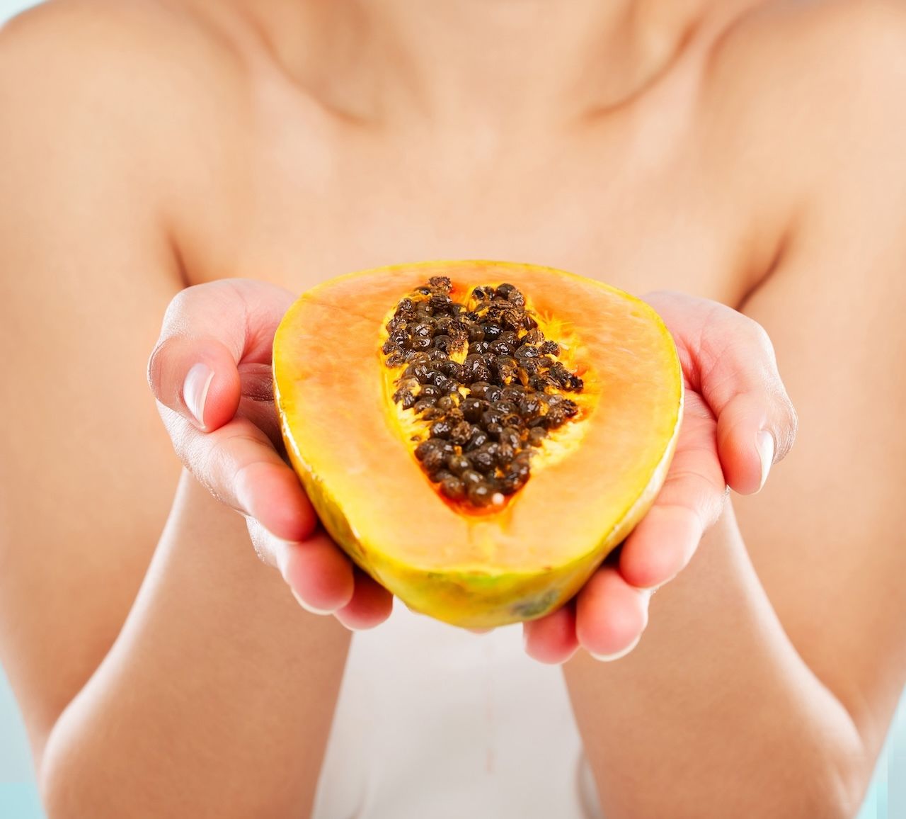 woman holding papaya, a natural source of exfoliating enzymes